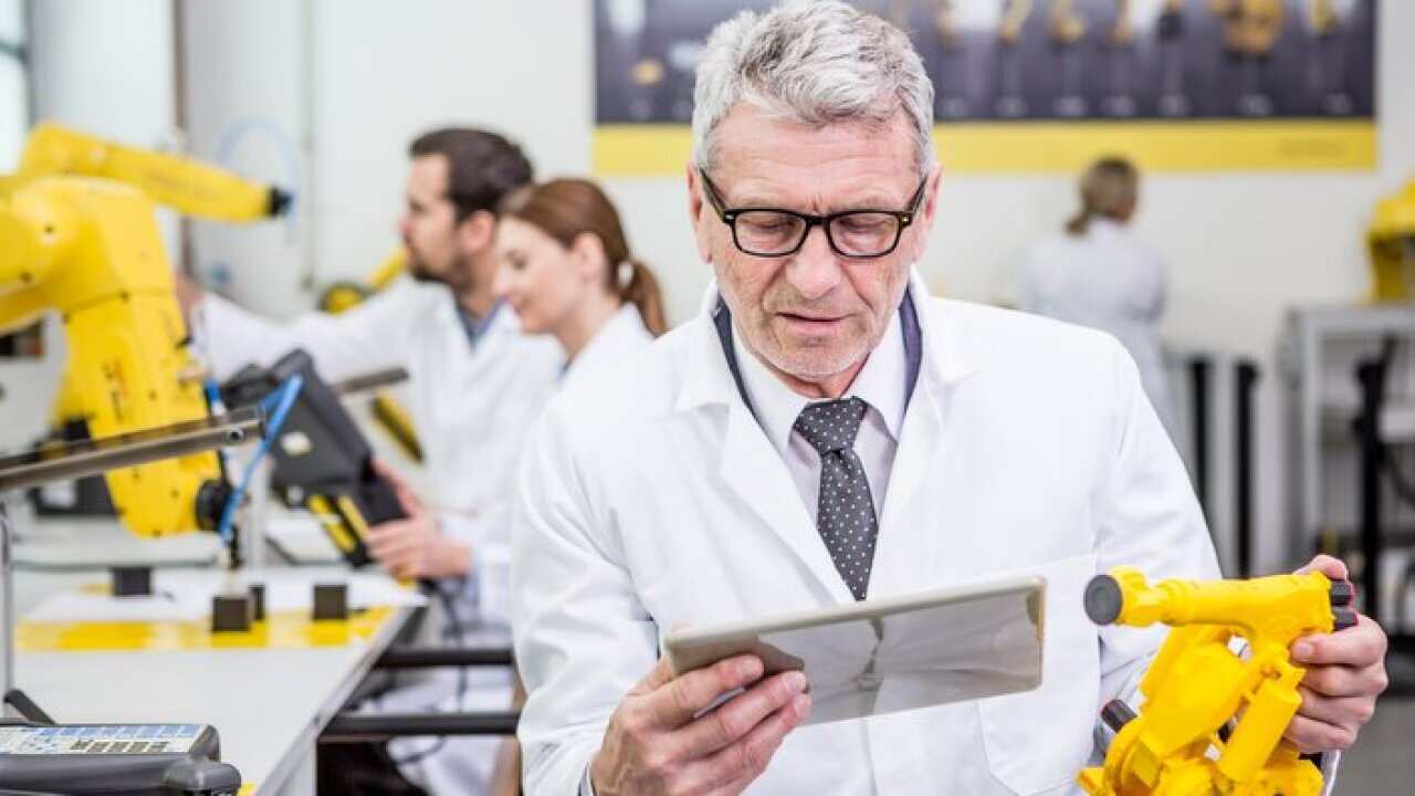 Engineer holding tablet and model of an industrial robot