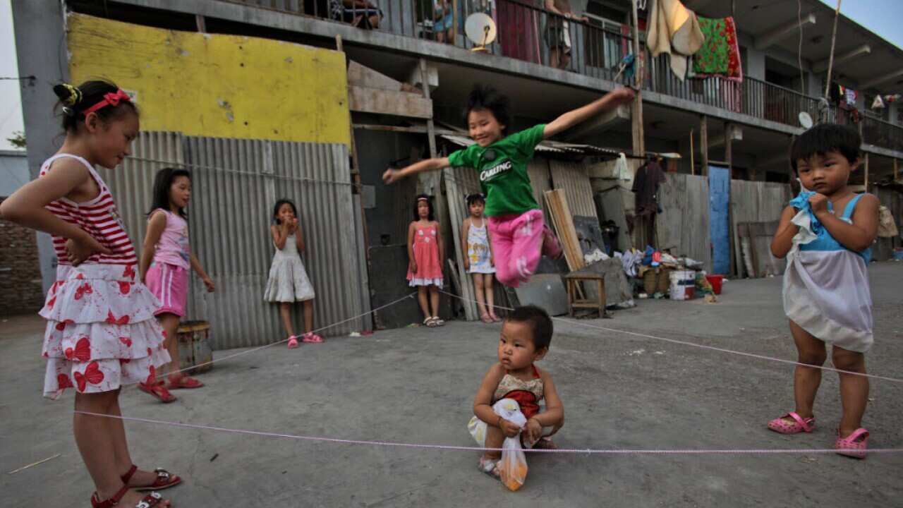 A Chinese girl jumps rope while playing with other girls, in a Hutong, or alleyway in Beijing, China, in 2010.