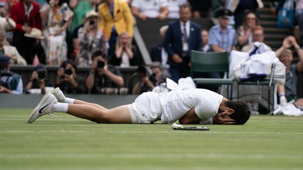 A man with his hands on his face lies face down on the ground.