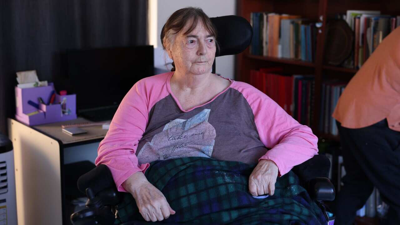 An older woman sitting in a chair with a blanket