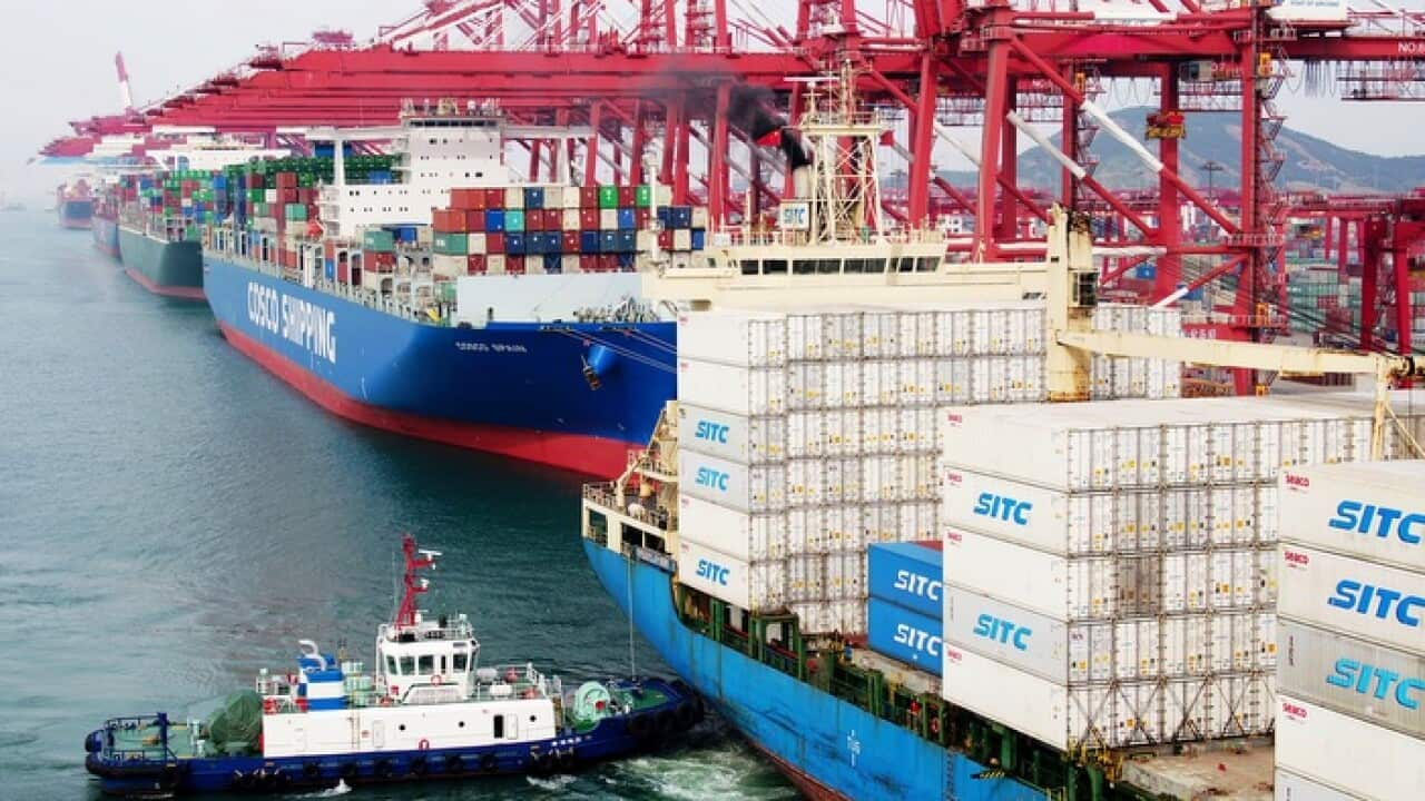 A barge pushes a container ship to the dockyard in Qingdao in eastern China's Shandong province.