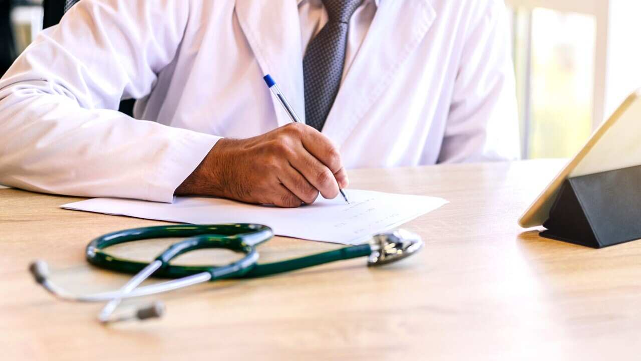 Indian doctor write medical prescription at his working place.