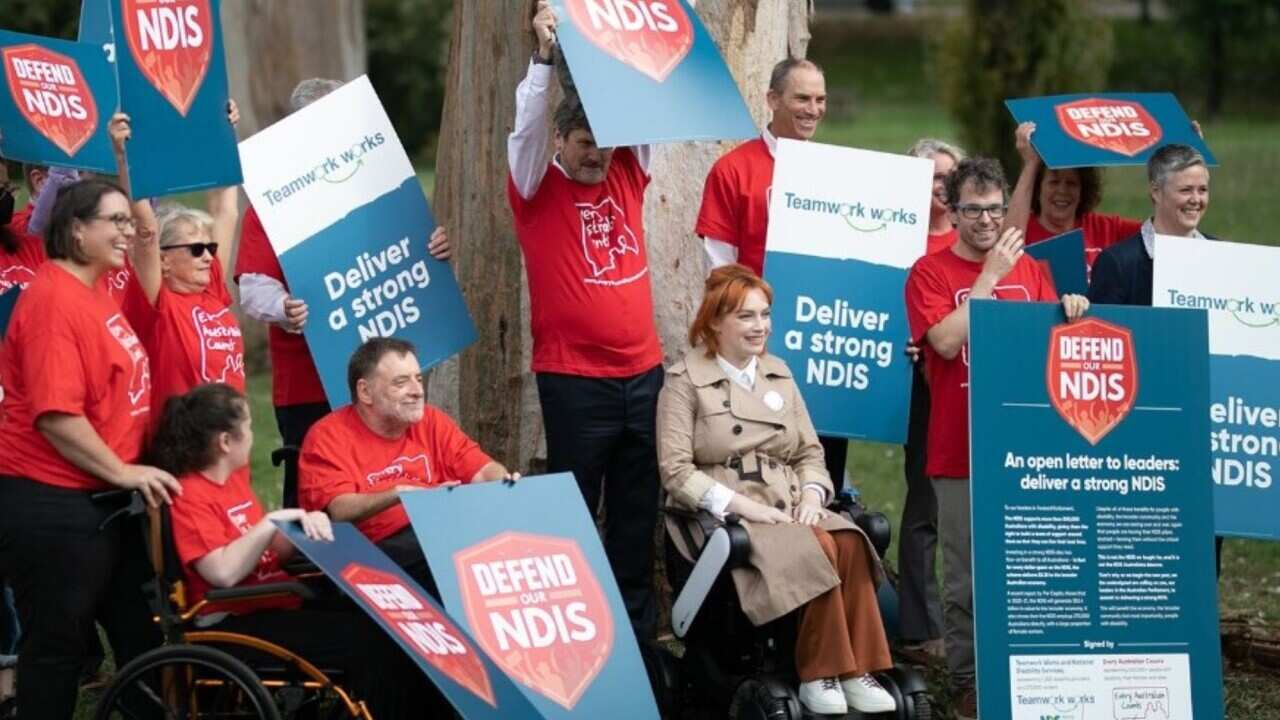 NDIS supporters hold signs calling for a "strong NDIS".