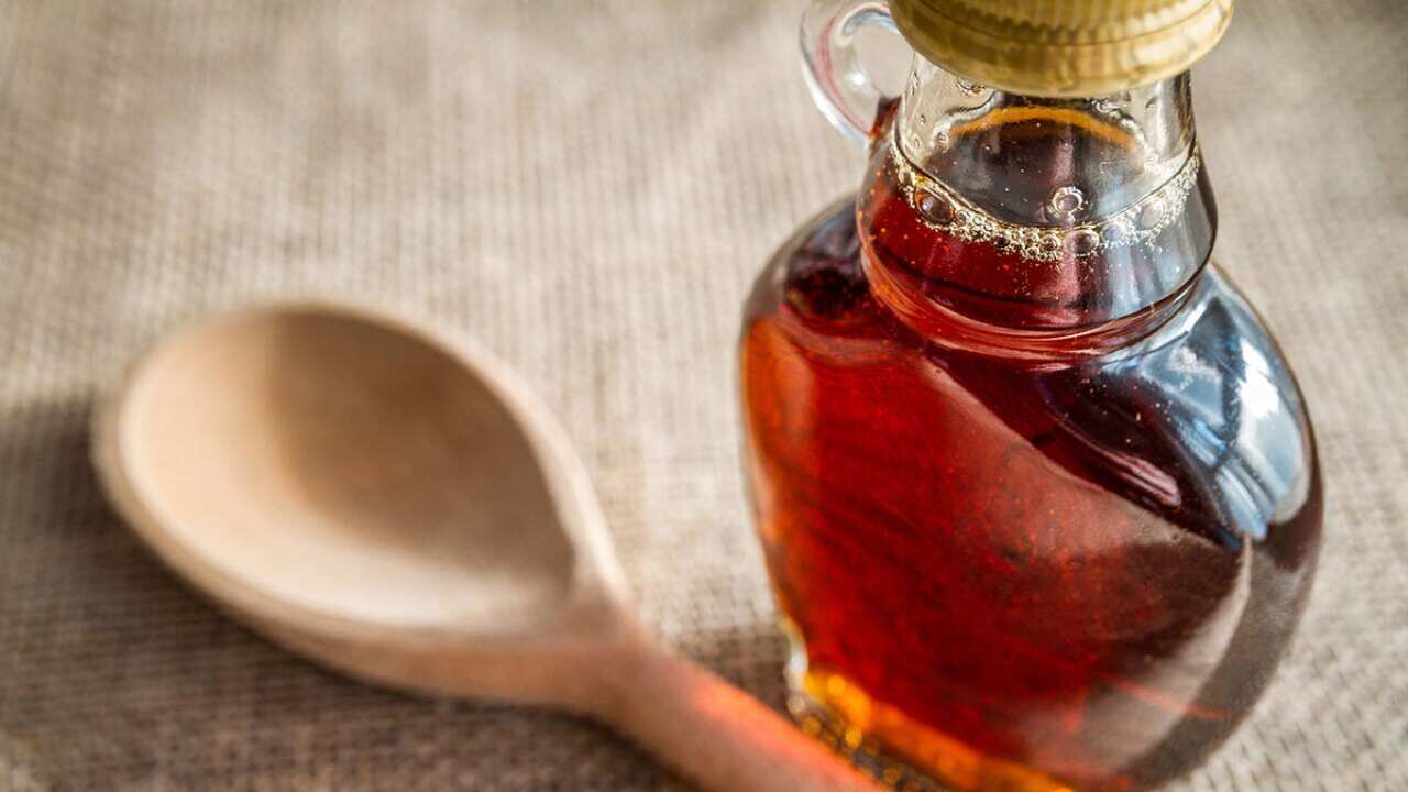 Bottle of maple syrup with wooden spoon