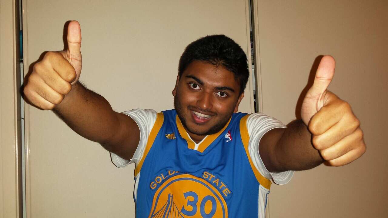 Young South Asian boy wearing basketball jersey top and giving the camera a thumbs-up.