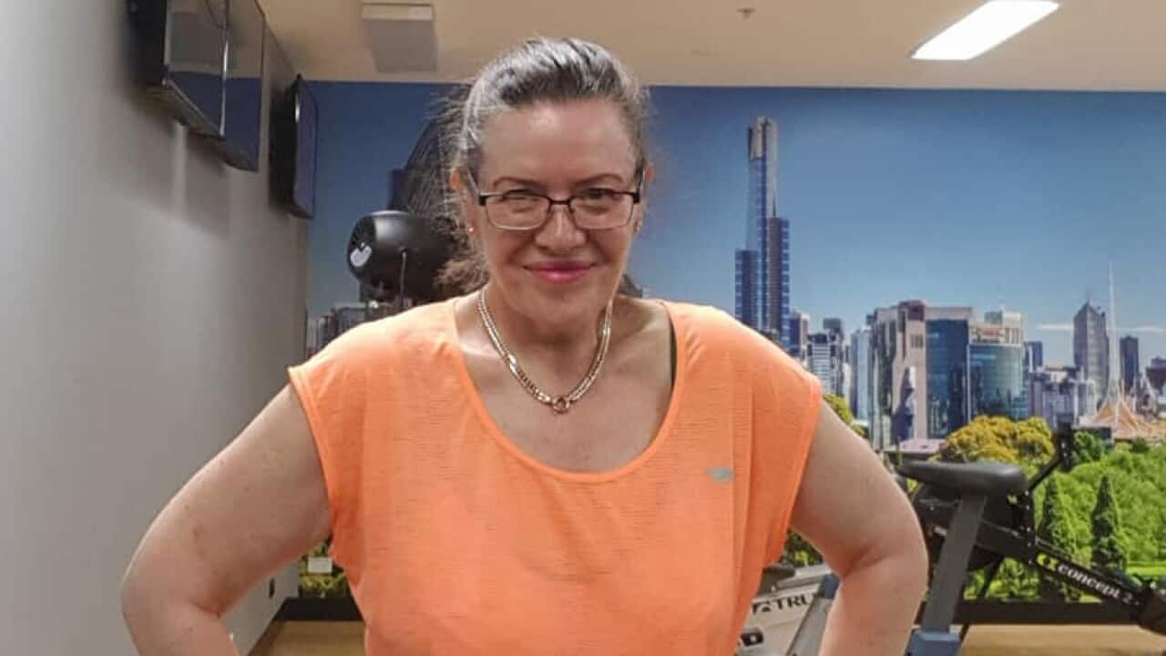 A woman wearing black tights and an orange t-shirt standing in a gym