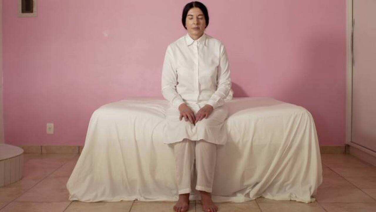 Artist Marina Abramovic sitting on a bed