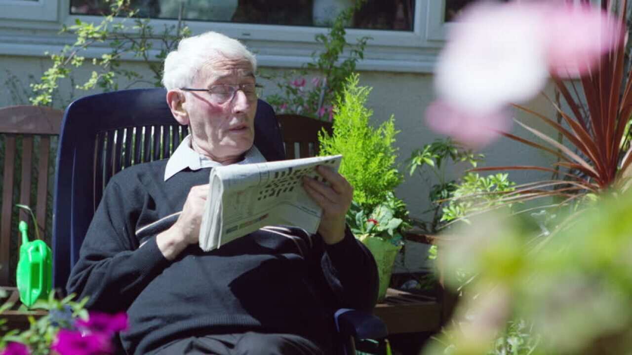 An old man is playing crossword