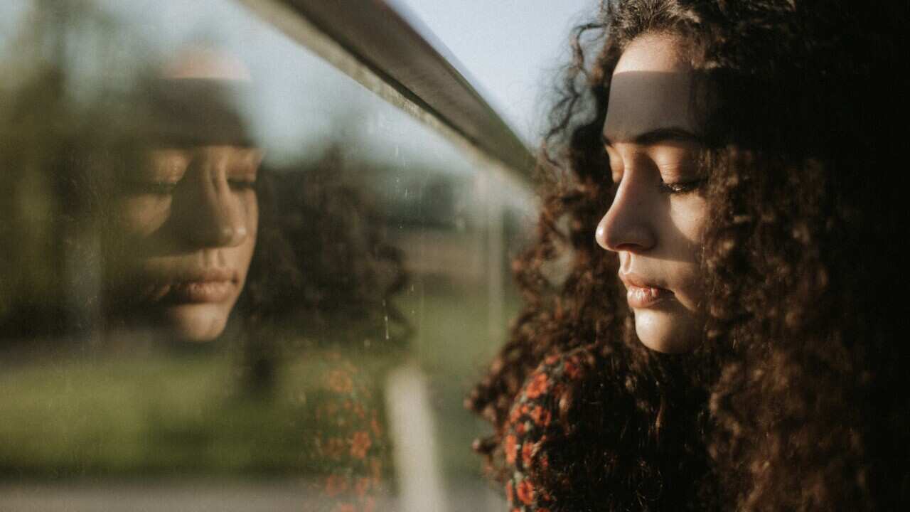 Stock photo of woman looking through window