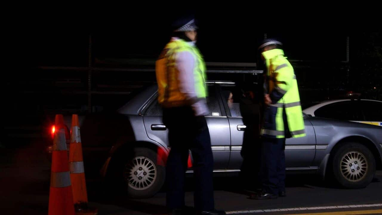 A police officer stops a motorist at a drink driving check point