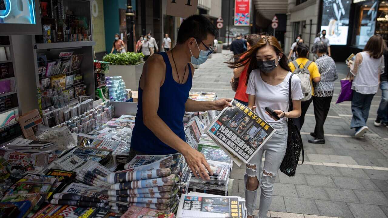 A woman buys a copy of Apple Daily newspaper at a news stand in Hong Kong, China, 18 June 2021. The pro-democracy newspaper made print-run of 500,000 for 18 June 2021, a day after Hong Kong’s national security police arrested five directors at the newspap