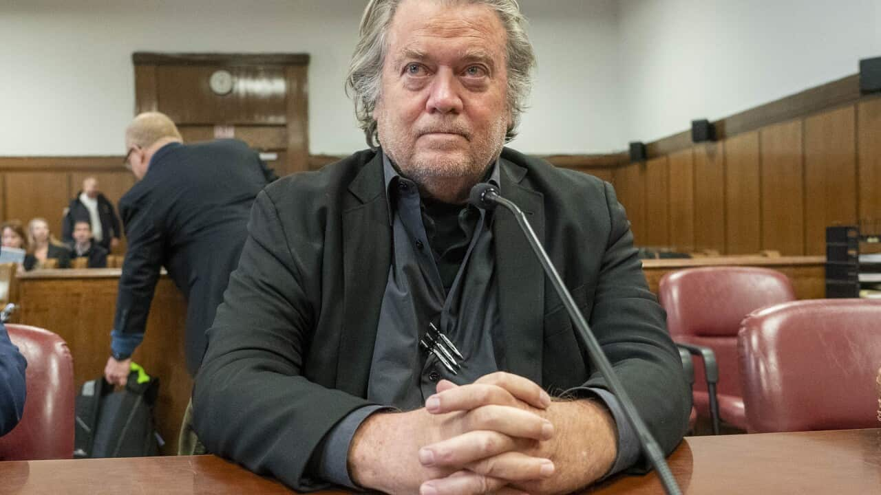 Steve Bannon sitting at a desk behind a microphone in a courtroom.