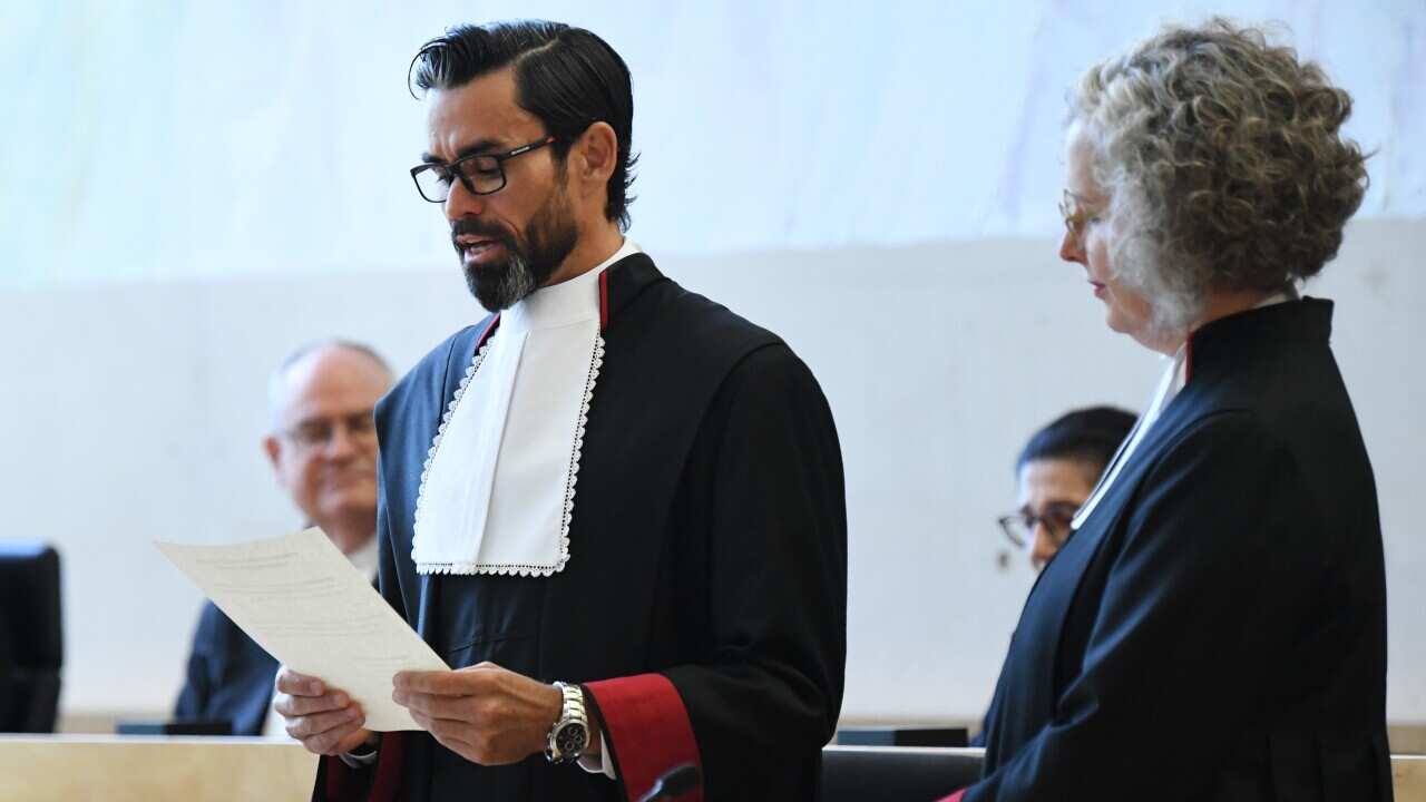 Dressed in judges robes, Lincoln crowley reads his swearing in statement as others look on