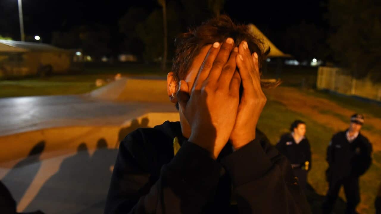 An aboriginal youth covers his face at a skate park