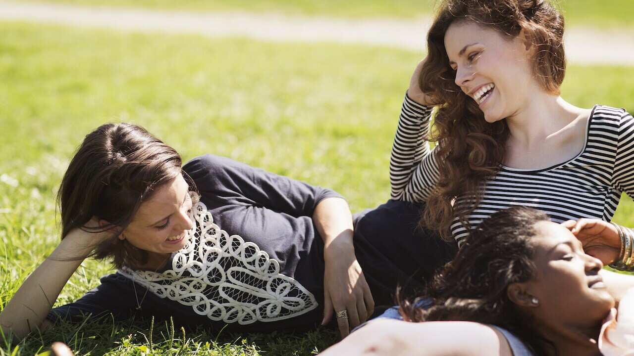 Smiling friends relaxing at park