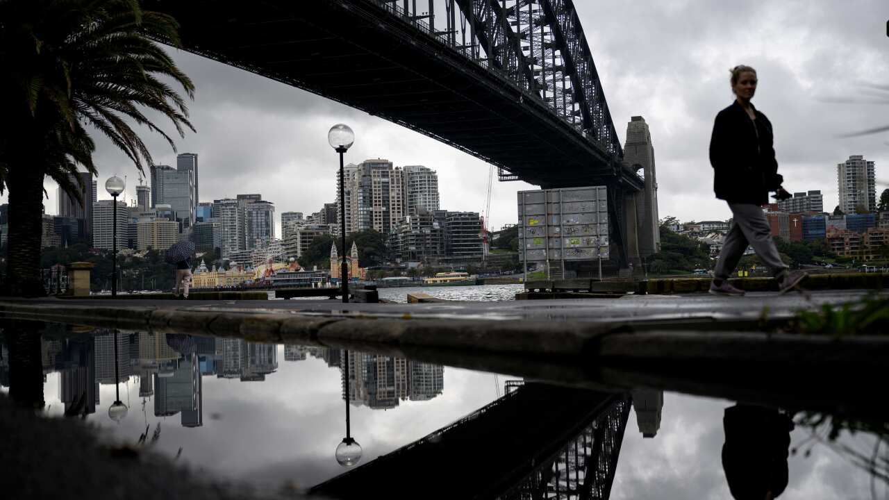 The Harbour Bridge is seen as people walk by in Sydney,