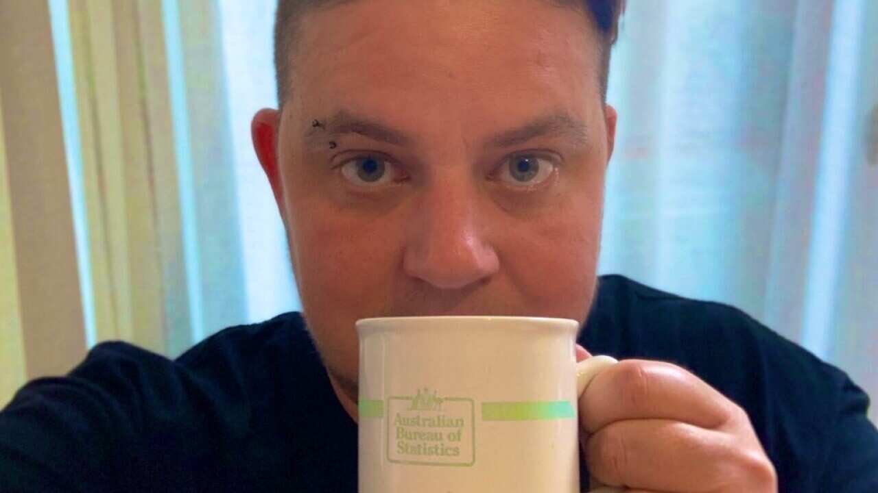 Switchboard CEO Joe Ball holding an Australian Bureau of Statistics mug up to his face.