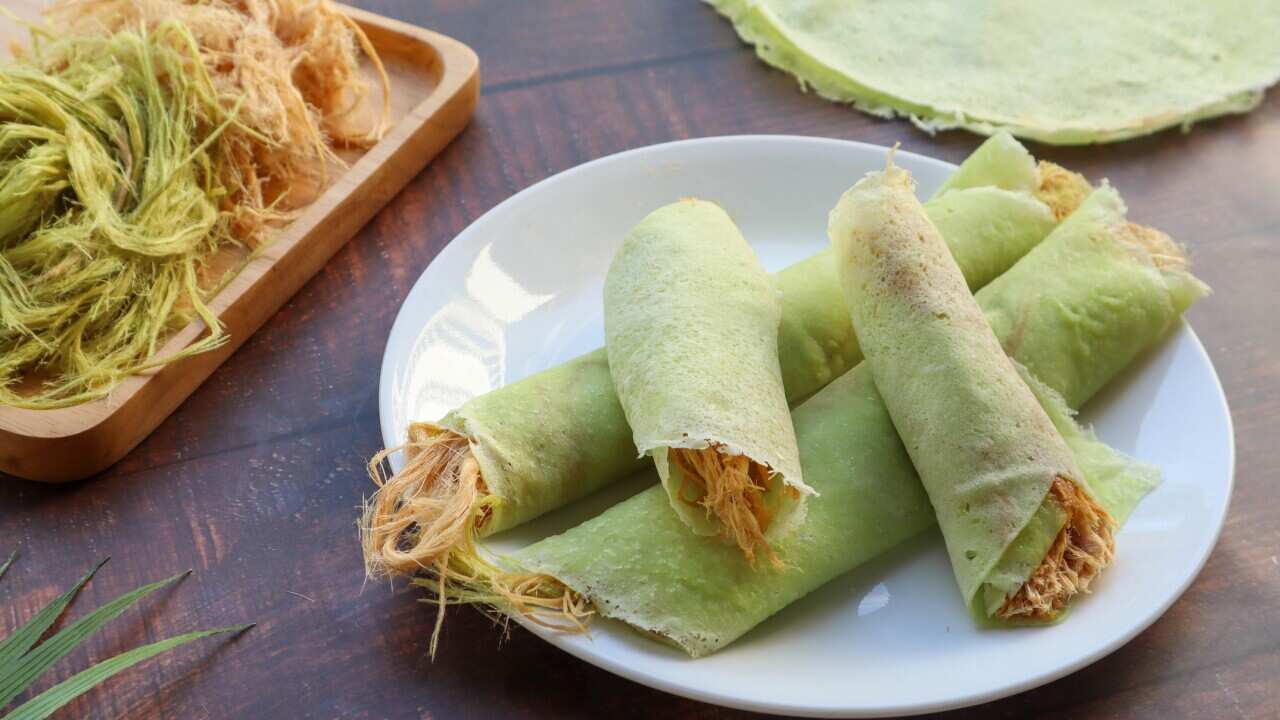 Roti sai mai - Thai dessert of cotton candy burrito pancake or crepe at top close up view of wood table.