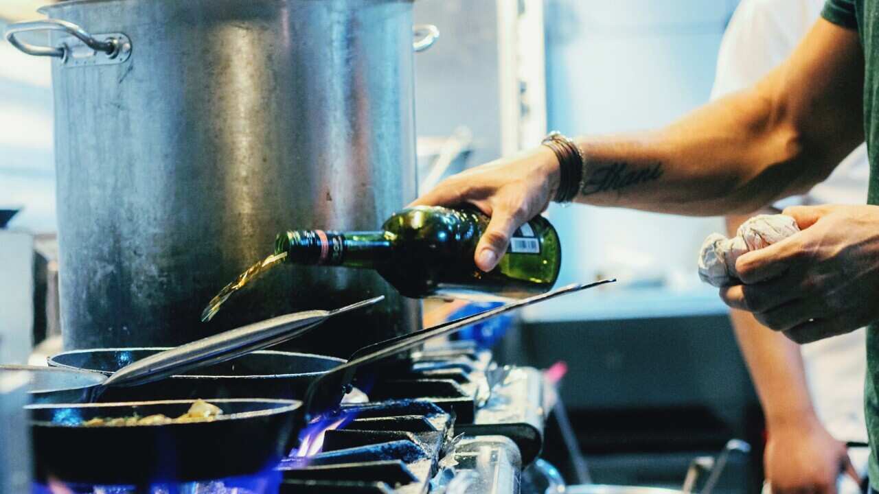 Chef Pouring Wine On Pan In Restaurant Kitchen