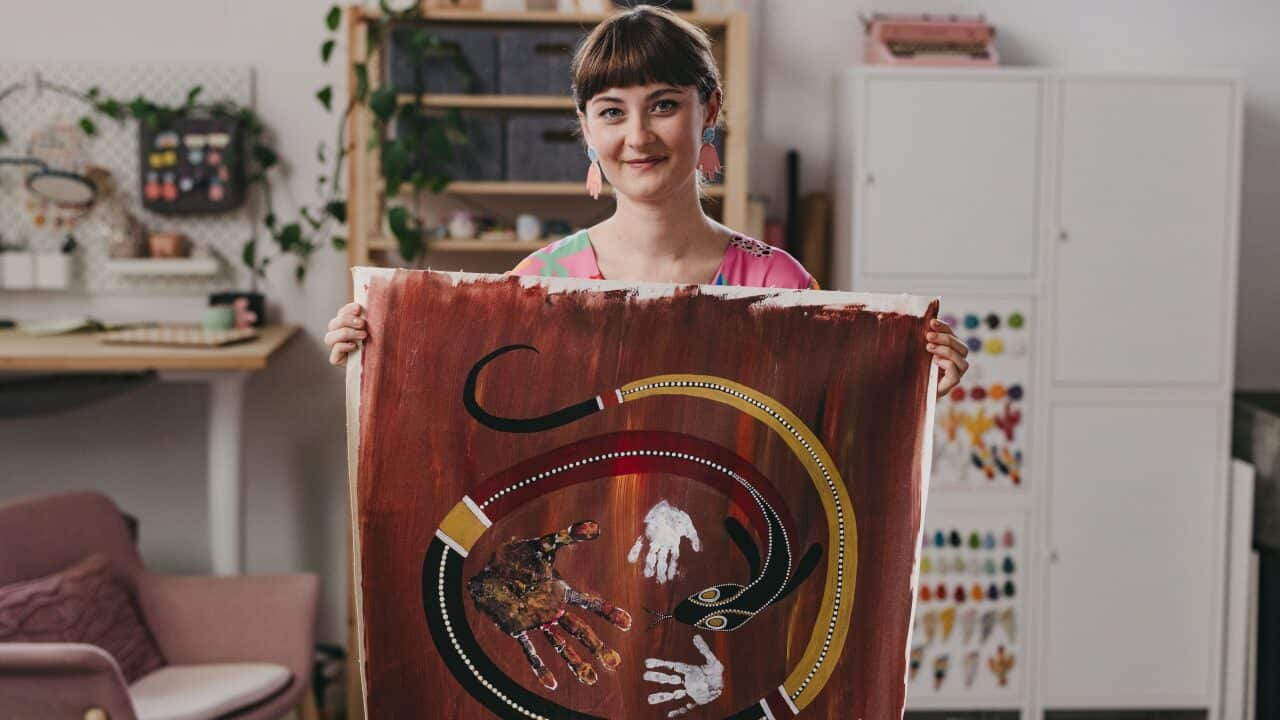 Nirrimi Firebrace holds up a painting she painted when she was young with her father and brother