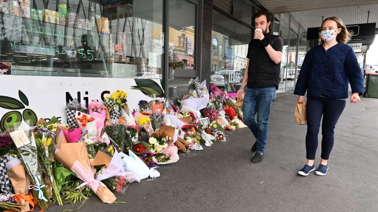 People walk past a floral tribute to a delicatessen owner who died from Covid-19 in Melbourne last year. (file)