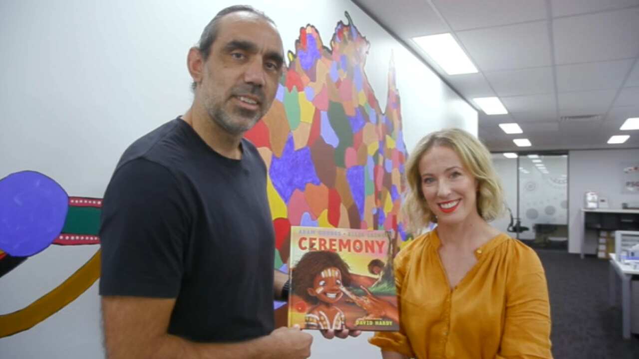 Adam Goodes holds his children's book with Ellie Laing