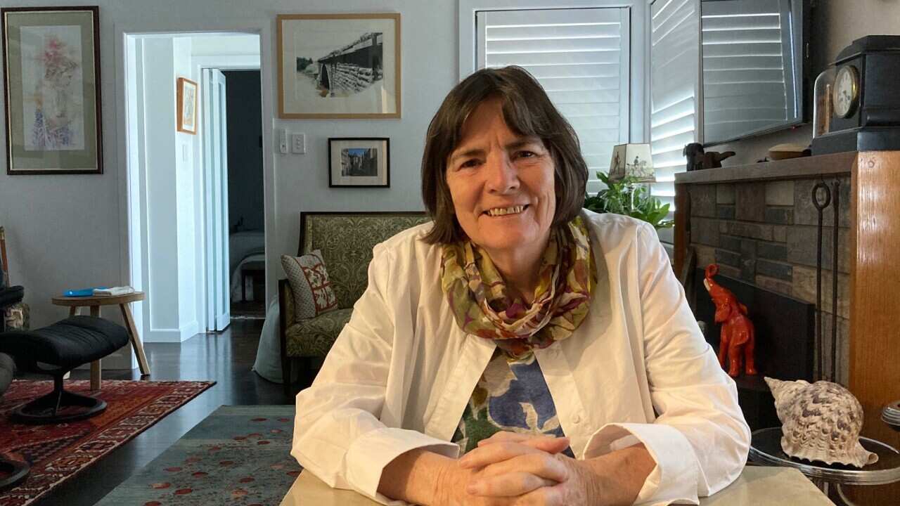 an older woman sitting at a table wearing a scarf