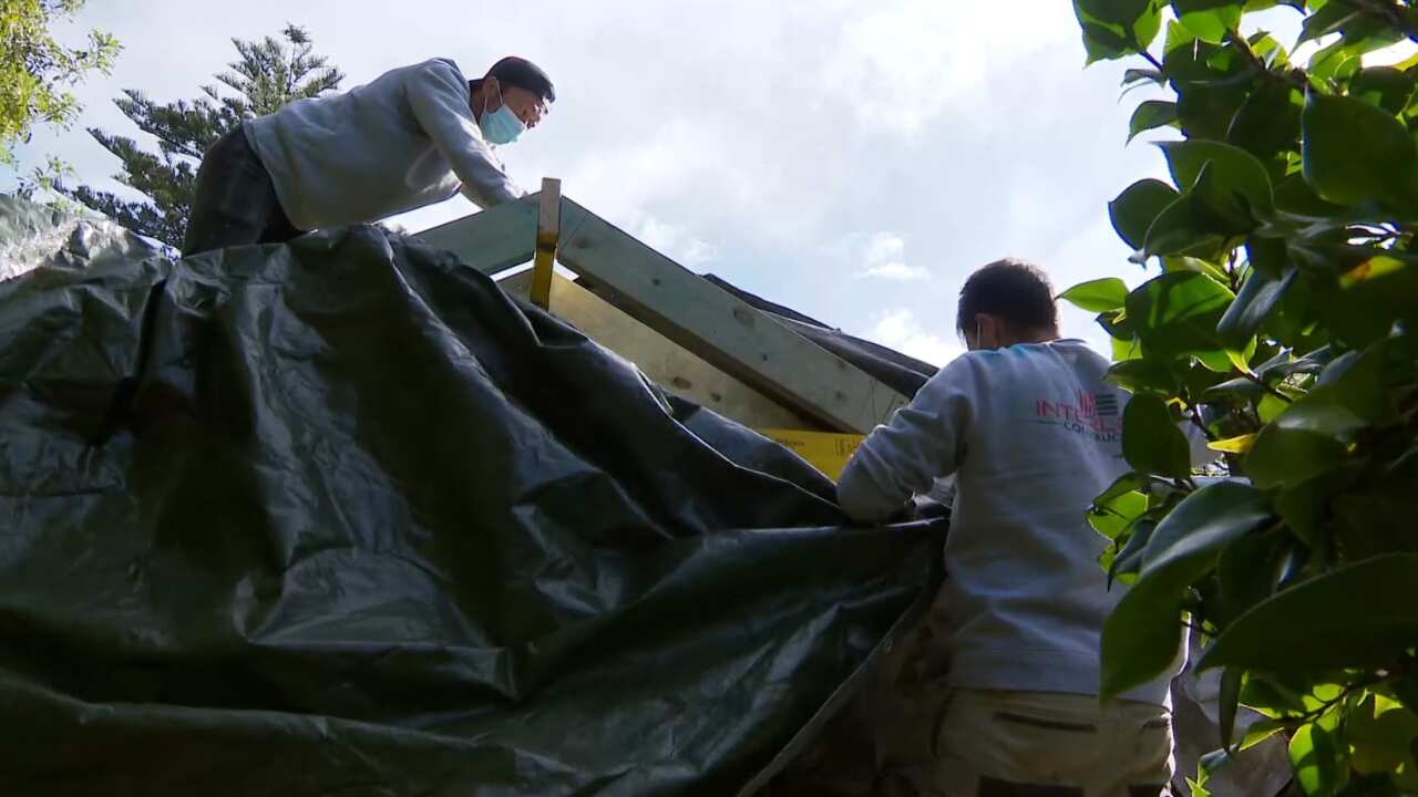 Nick Abraham, founder of Interlock Construction, (right) works with a colleague to secure a building site ahead of the new restrictions taking effect. 