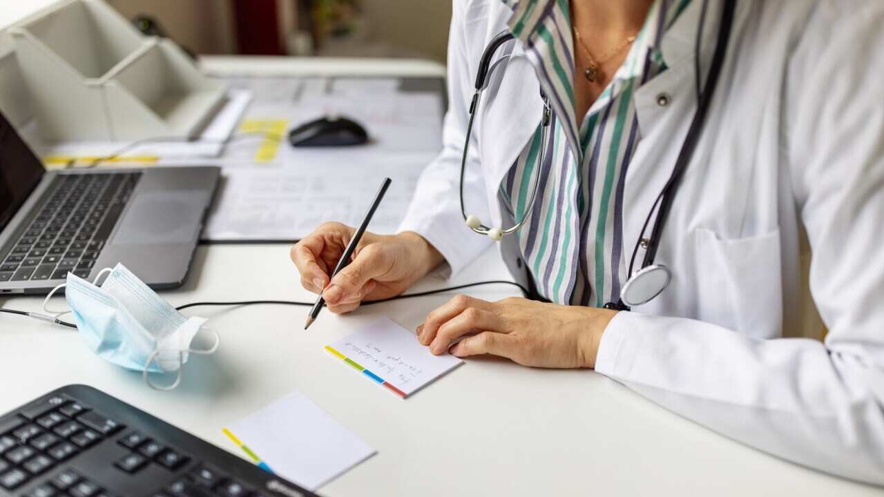 Doctor making notes while on video call with patient
