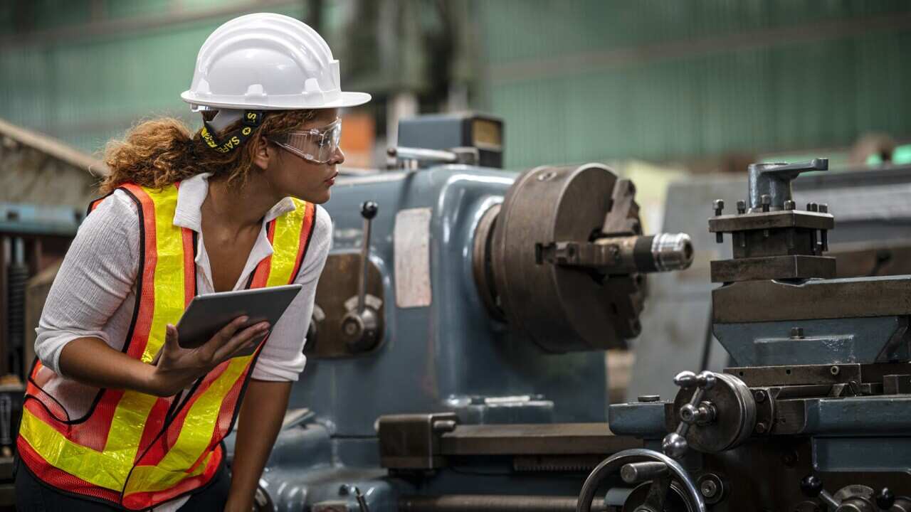 An engineer inspects a lathe