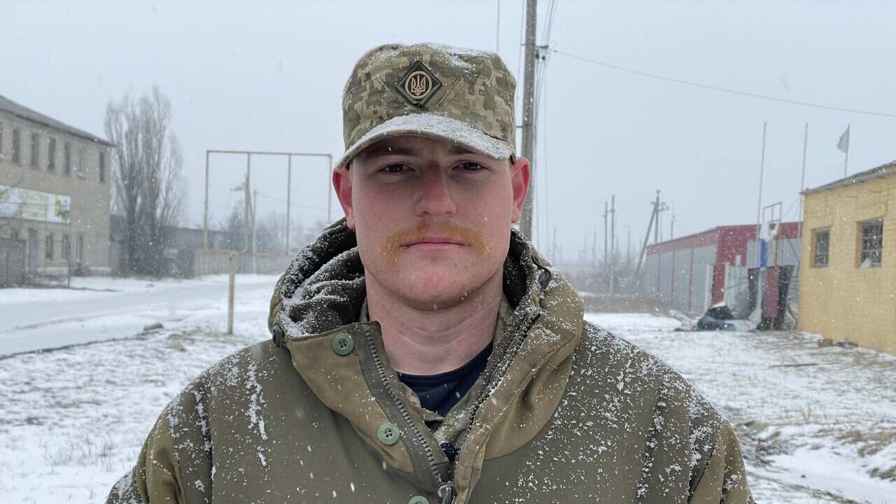 A man wearing army clothing standing outside in the snow