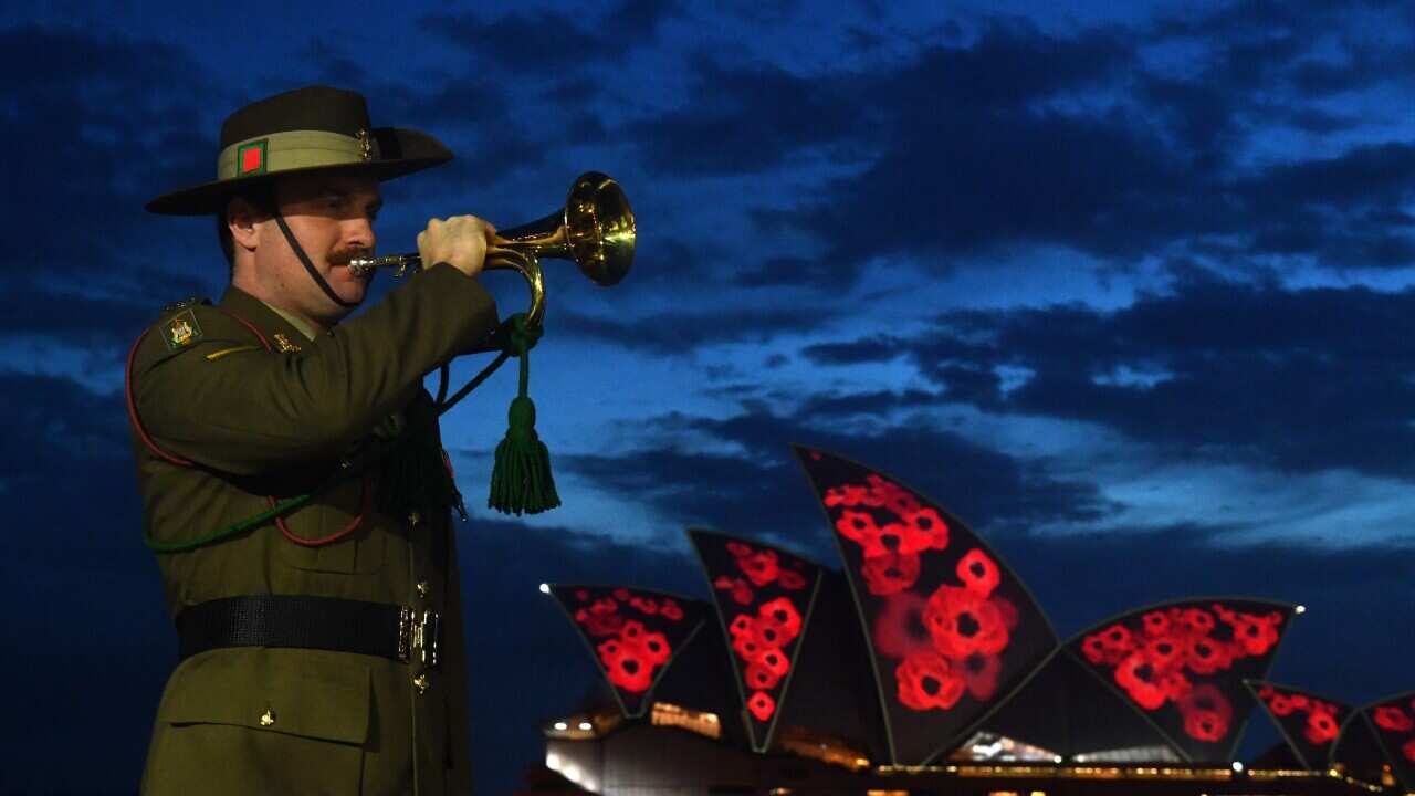 Bugler Lance Corporal Justin Williams plays “The Last Post” as poppies are projected on to the Sydney Opera House sails during a Remembrance Day 2021 Dawn Service at Campbells Cove, Sydney, Thursday, November 11, 2021.