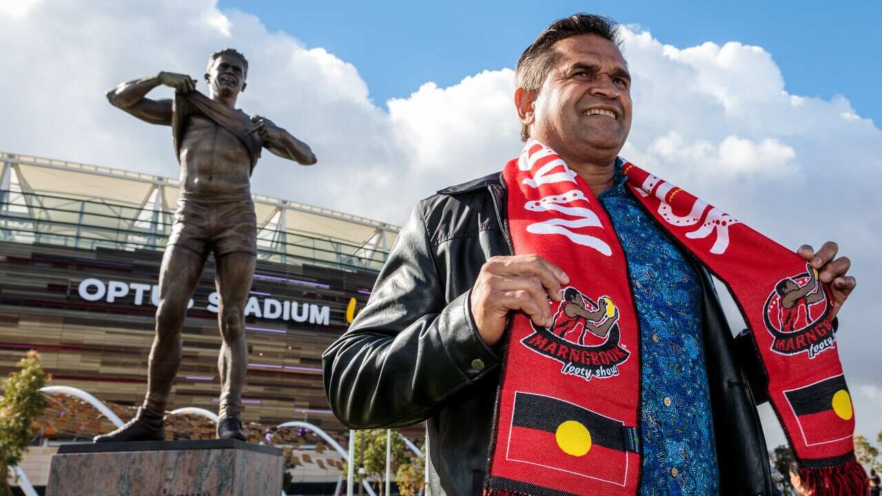 Former St Kilda Saints player and Western Australian-born Noongar man Nicky Winmar stands in front of his statue at Optus Stadium in Perth.