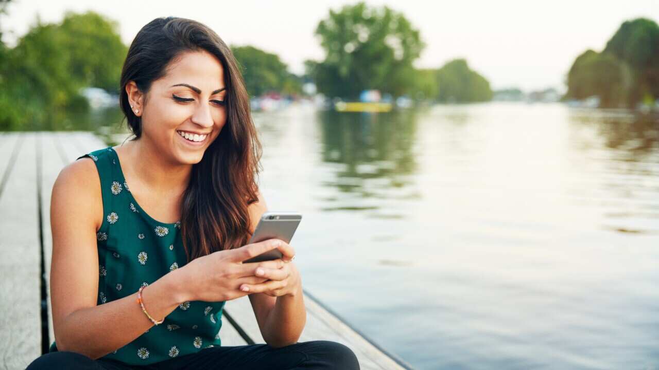 Young woman with smartphone on jetty.