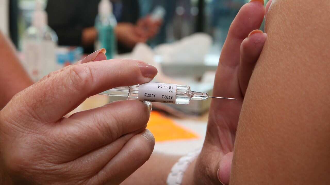 A handle holding a syringe about to inject someone's arm