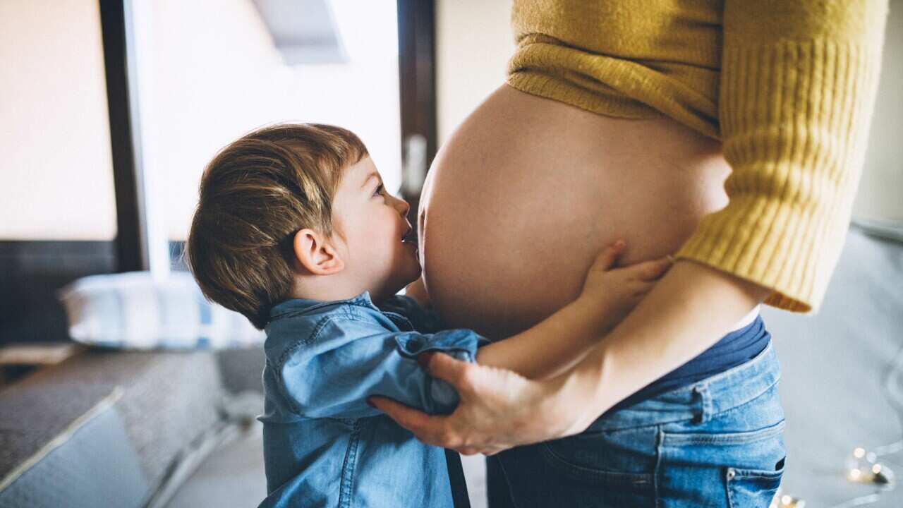 Young boy kissing his mother's pregnant belly