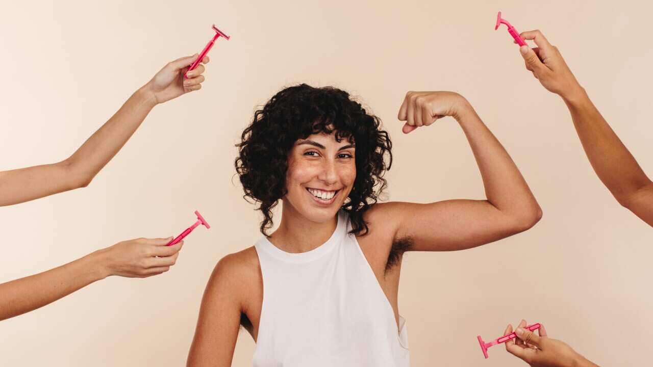 Empowered woman flexing her unshaven underarm