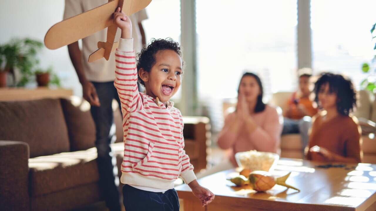 Little happy multiracial boy playing with model aircraft.