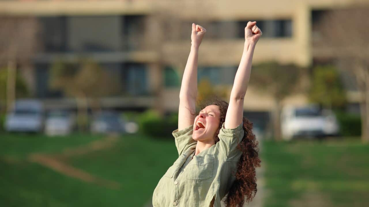 Excited woman raising arms celebrating success