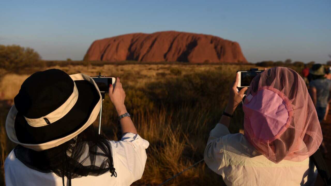 Tourists take photo at Uluru - AAP