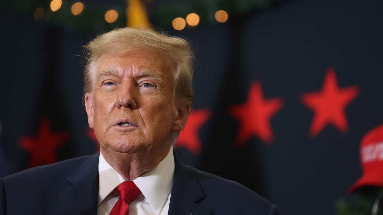 Donald Trump speaking in front of American flags.