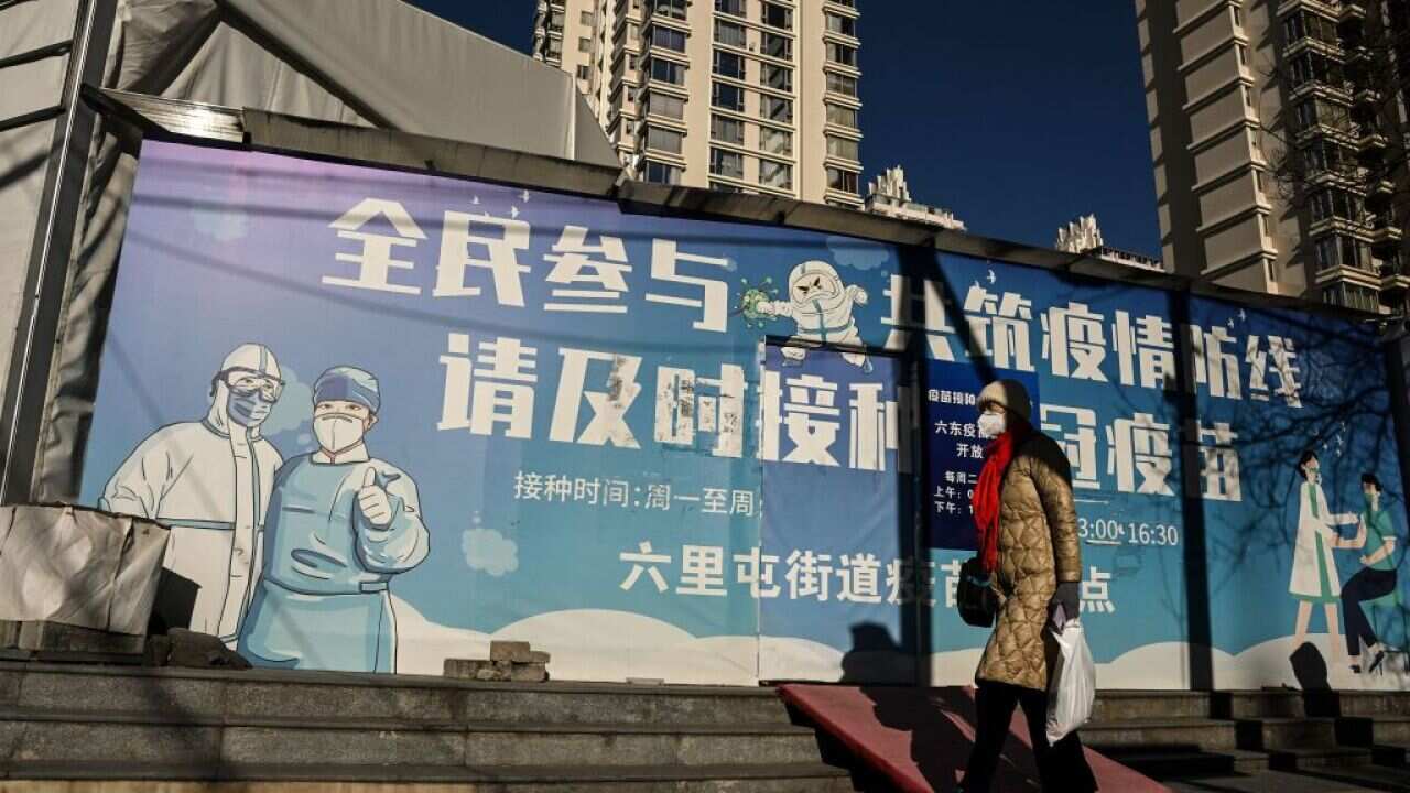 A woman wearing a face mask amid the COVID-19 pandemic walks along a street in Beijing.