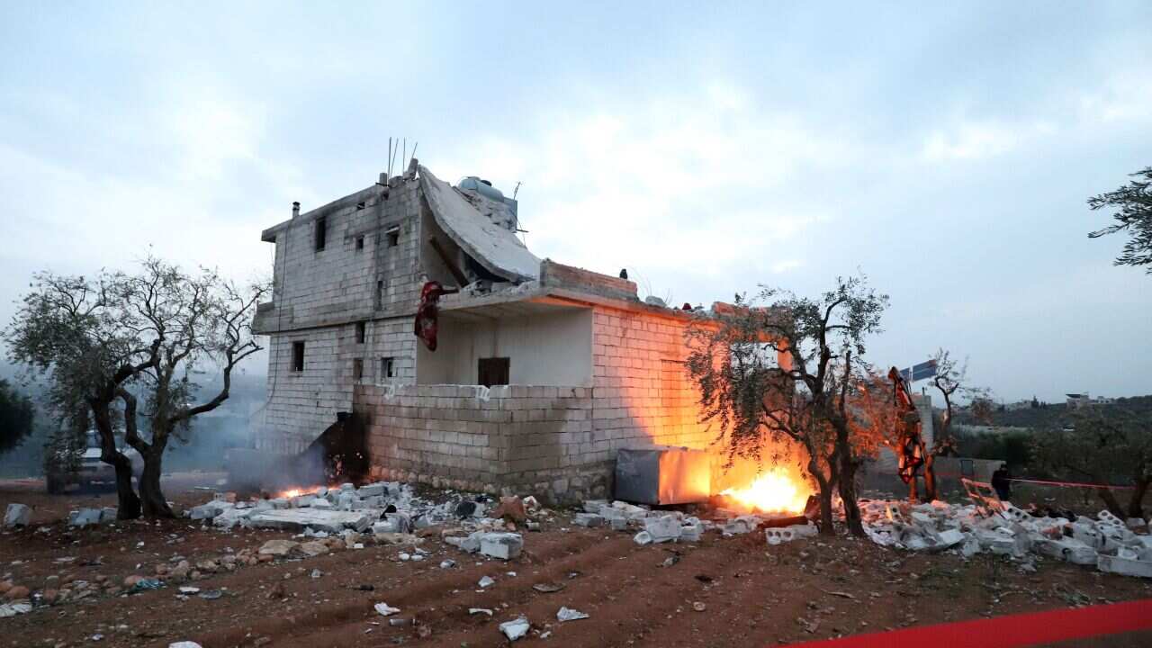 Red tape is extended and objects are set on fire, around the hous in which the leader of Islamic State (IS) group Amir Mohammed Said Abd al-Rahman al-Mawla died, during an overnight raid by US special forces, in the town of Atme in Syria's northwestern pr