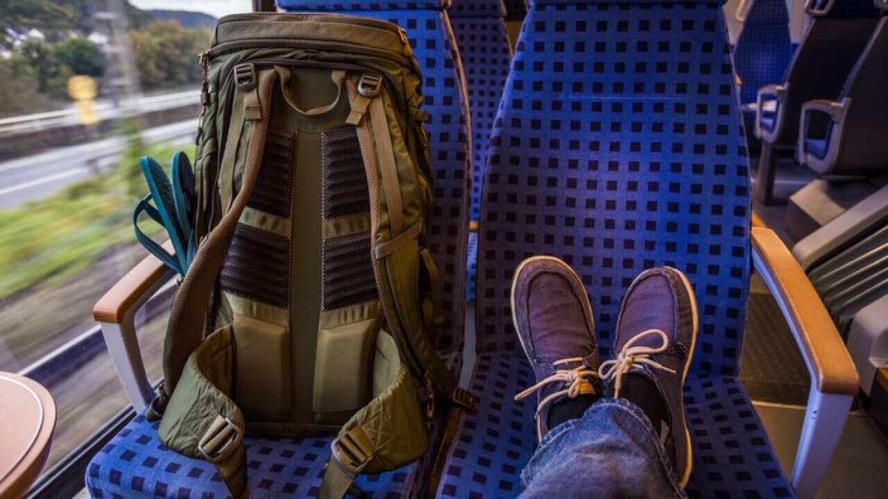 Backpacker's feet resting on seat in train