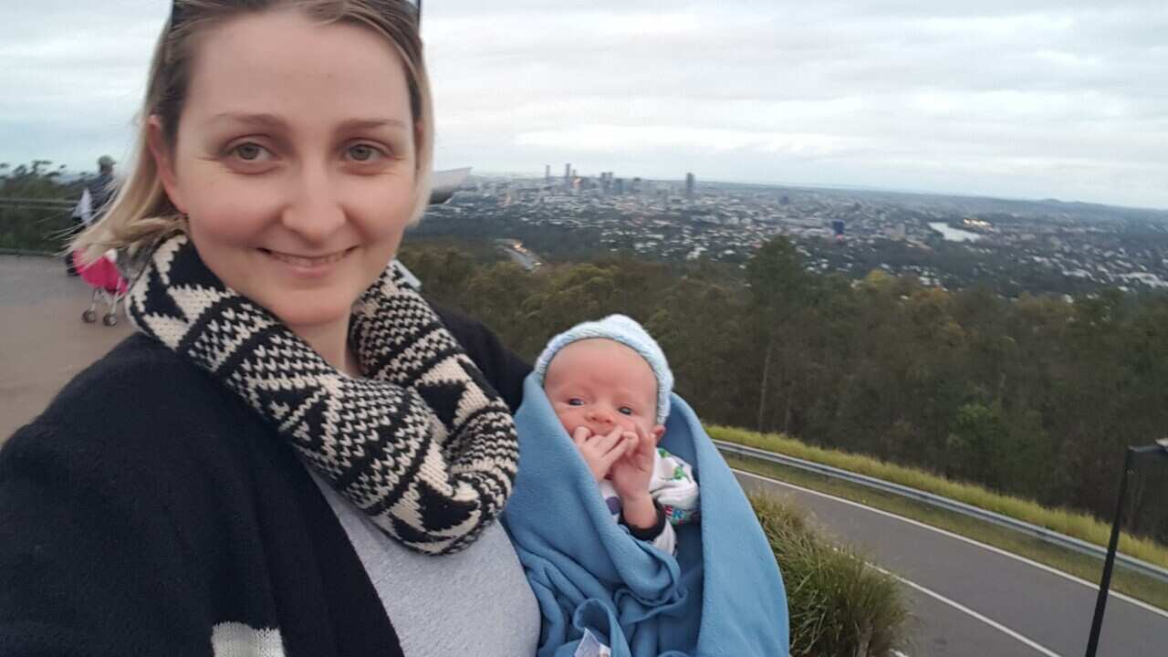 A woman and her baby standing at a lookout over a city