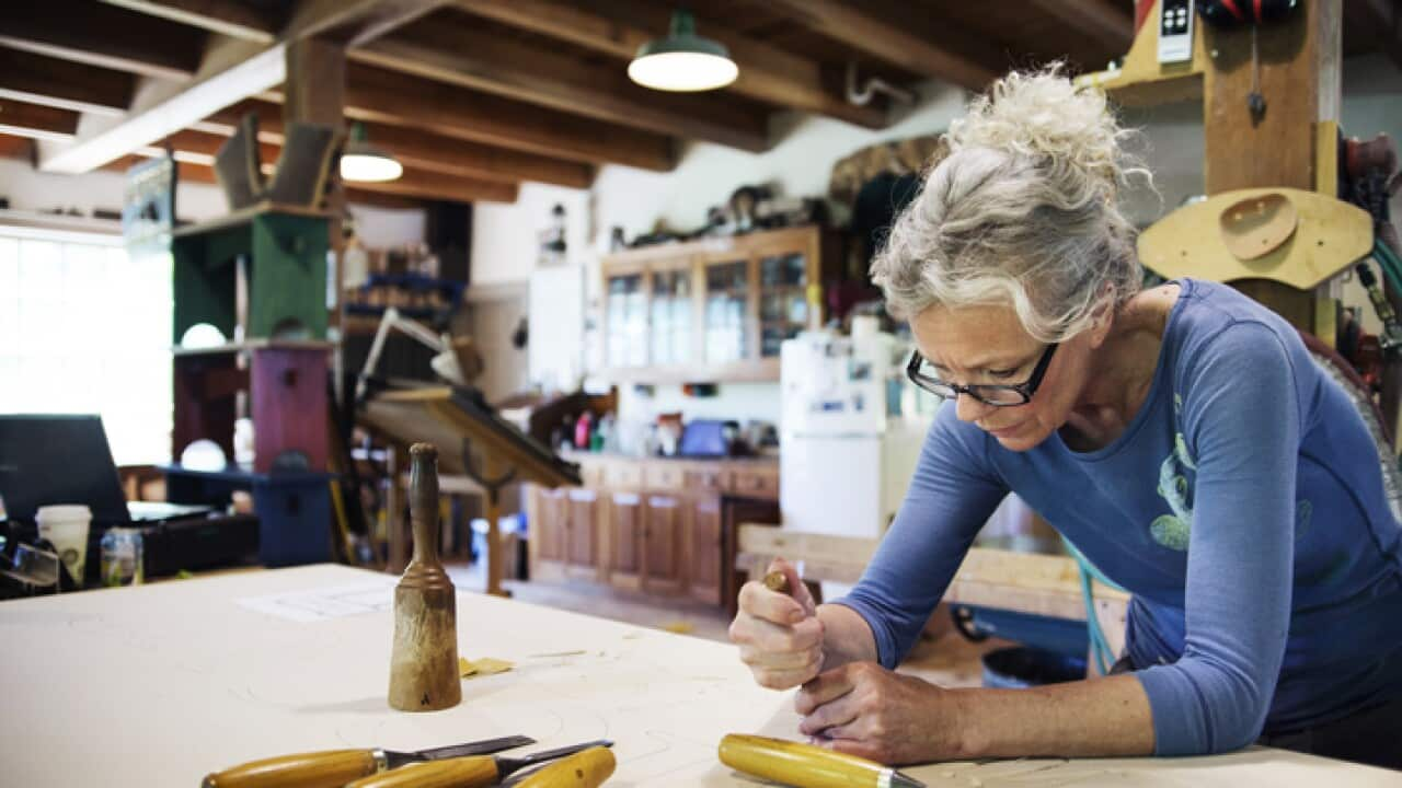 Concentrated female using chisel for shaping wood in workshop