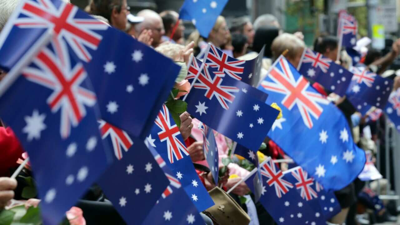 People wave flags as an ANZAC Day parade marches by in Sydney, Australia, Saturday, April 25, 2015.