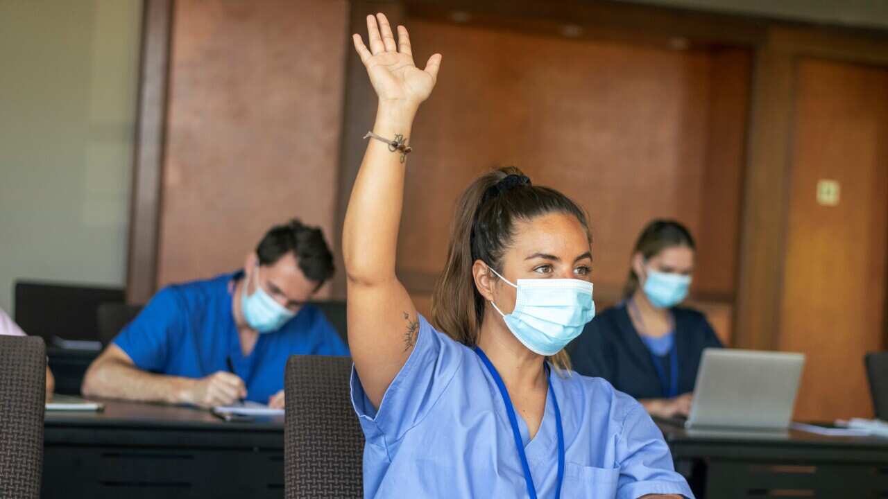 Female medical student raising hand in class