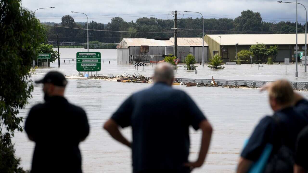 People watch on as debris carried by floodwater in the swollen Hawkesbury river in Sydney.