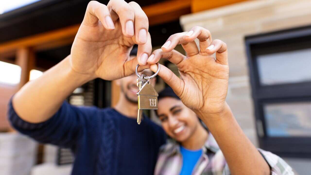 A young couple happily displaying a house key.